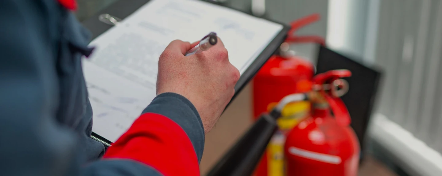 Inspector recording fire extinguisher inspection details