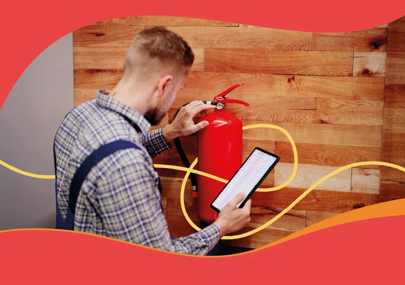 Person checking a mounted fire extinguisher with a tablet