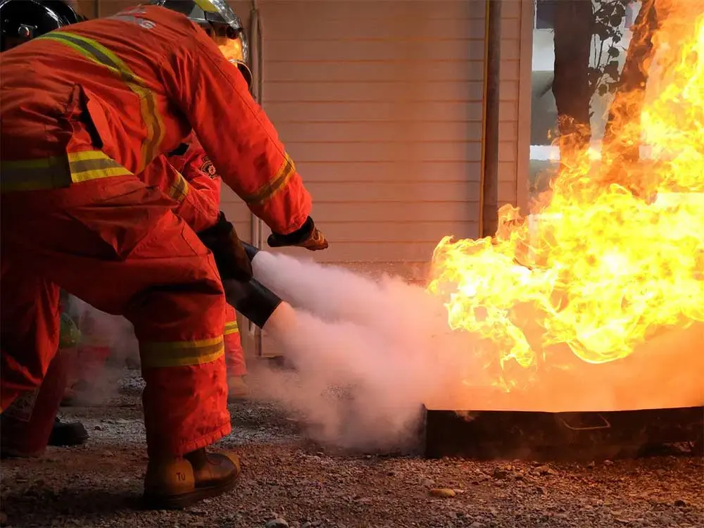 Firefighter using an extinguisher outside a building